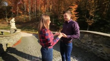 Sevgi dolu bir çift sonbaharda parkta yürüyor. Güneşli bir sonbahar gününde bir aşk hikayesi. göl ve bringe