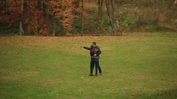 Um casal amoroso caminha no outono no parque. Uma história de amor num dia ensolarado de Outono. lago e franja — Vídeo de Stock