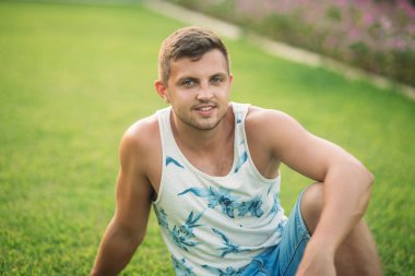 Gülümsüyor adam şort ve gömlek yaz aylarında park yakınlarında yürür