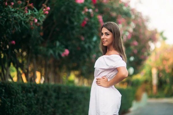 Sexy Dame im weißen Kleid steht neben den Blumen — Stockfoto