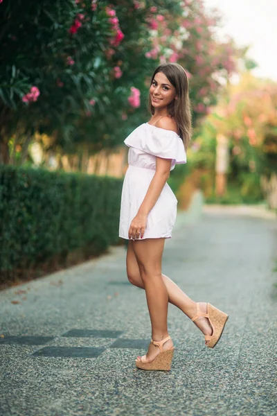 Сексуальна леді в білій сукні, що стоїть біля квітів — стокове фото
