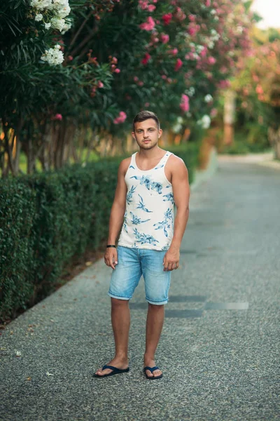 Hombre sonriente en pantalones cortos y camisa en verano camina cerca del parque — Foto de Stock