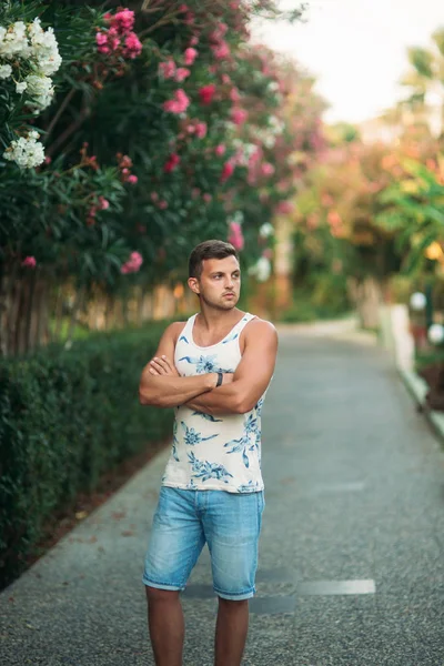 Gülümsüyor adam şort ve gömlek yaz aylarında park yakınlarında yürür