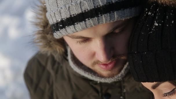 En ung kille och en tjej klädd i varma vinterkläder, njuta av förekomsten av varandra i en snöig vinter park — Stockvideo