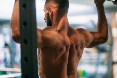 Genç bir atlet spor salonunda eğitiyor. Sırt ve göğüs kaslarının gösterir