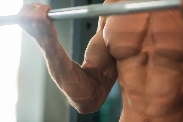 Un joven atleta entrena en el gimnasio. Trians bíceps musculares — Foto de Stock