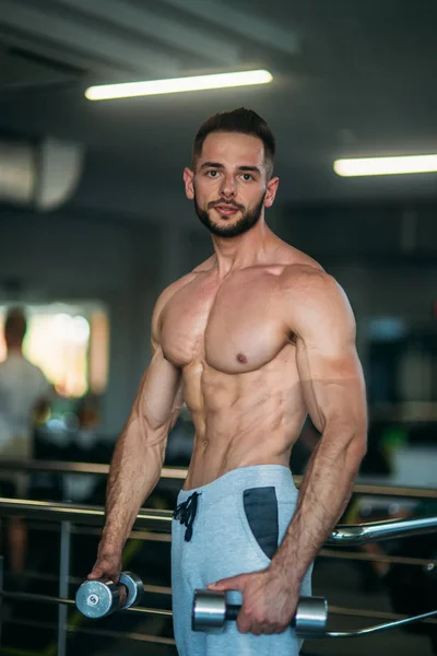 Un joven atleta entrena en el gimnasio. Trians bíceps musculares — Foto de Stock