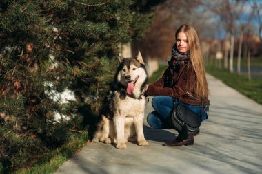 Gülümseyen bir kız ile bir köpek set boyunca yürüyor. Güzel husky köpek