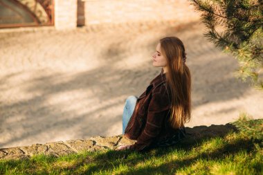 Güzel bir kız set yürüyor. Sarı saçlı ve kahverengi ceket. Bahar