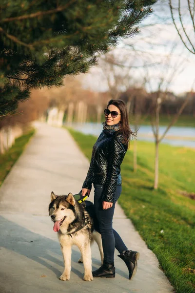Beautiful brunette lady walking with a dog along the embankment. Beautiful husky dog