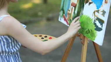 Park ve holding palet boya ile dışkı üzerinde güzel kız sanatçıdır