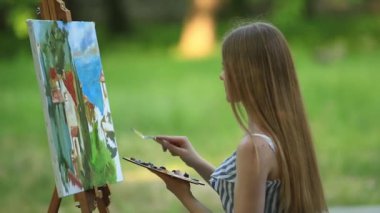 Park ve holding palet boya ile dışkı üzerinde güzel kız sanatçıdır