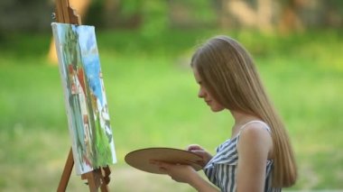 Park ve holding palet boya ile dışkı üzerinde güzel kız sanatçıdır