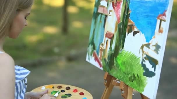 Linda artista menina está no banquinho no parque e segurando paleta com tintas — Vídeo de Stock