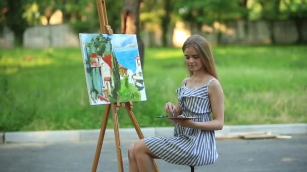 Bella ragazza artista è sullo sgabello nel parco e tenendo tavolozza con vernici — Video Stock