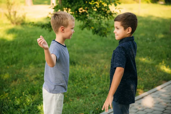 Dos niños juegan en el parque. Dos hermosos chicos en camisetas y pantalones cortos se divierten. Están sonriendo. —  Fotos de Stock