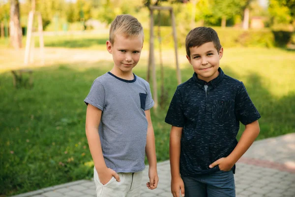 Çocuklar parkta oynuyorlar. İki güzel çocuk T-shirt ve şort iyi eğlenceler. Onlar gülüyor