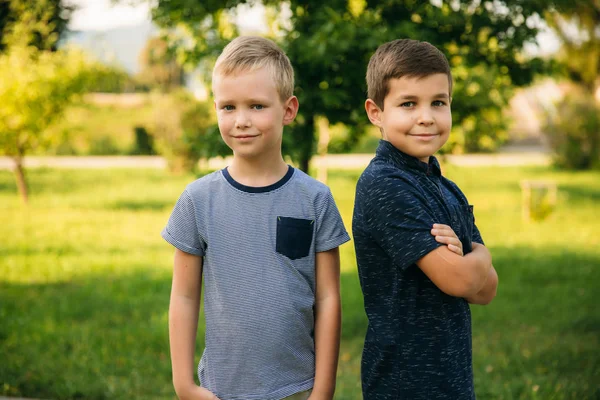 Dos niños juegan en el parque. Dos hermosos chicos en camisetas y pantalones cortos se divierten. Están sonriendo. —  Fotos de Stock