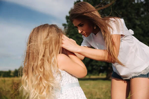 Familie vergnügt sich draußen beim großen Baum. Mutter und Tochter gehen durch das Gras — Stockfoto