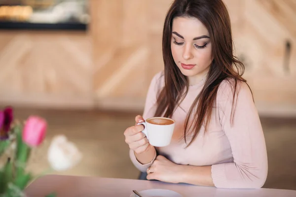 Gyönyörű lány ül a kávézóban, és iszik cappuccino — Stock Fotó