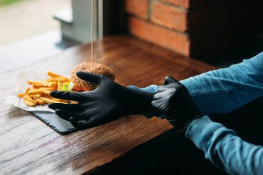 Adam siyah eldiven hamburger onun elinde alır.
