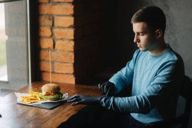 Adam siyah eldiven hamburger onun elinde alır.