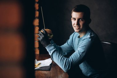 Adam siyah eldiven hamburger onun elinde alır.