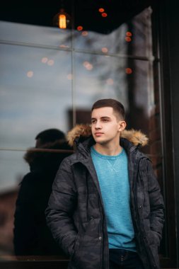 Gri ceketli adamı sokakta duran ve bir fotoğrafçı için poz