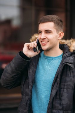 Gri ceketli adamı ayakta dışında ve bir telefon kullanma