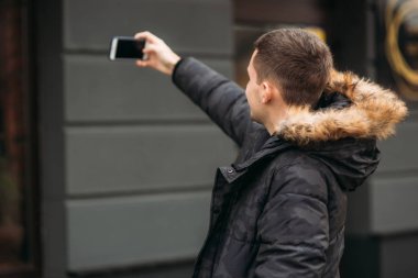 Gri ceketli adamı ayakta dışında ve bir telefon kullanma