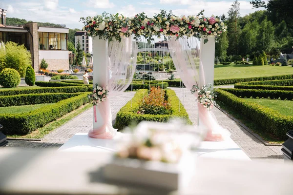 Weddind decoration on open air. Floral decor of a beautiful white arch. Beautiful beckground view of trees — Stock Photo, Image