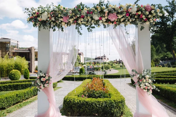 Weddind decoration on open air. Floral decor of a beautiful white arch. Beautiful beckground view of trees — Stock Photo, Image
