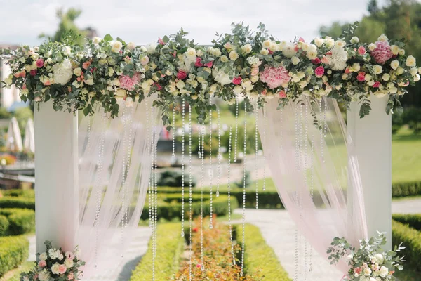 Weddind decoration on open air. Floral decor of a beautiful white arch. Beautiful beckground view of trees — Stock Photo, Image