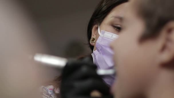 Medicine, dentistry and healthcare concept - female dentist with kid patient at dental clinic adjusting chair — Stock Video