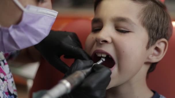 Un niño visita a un dentista, una doctora trata a un niño con dientes — Vídeo de stock