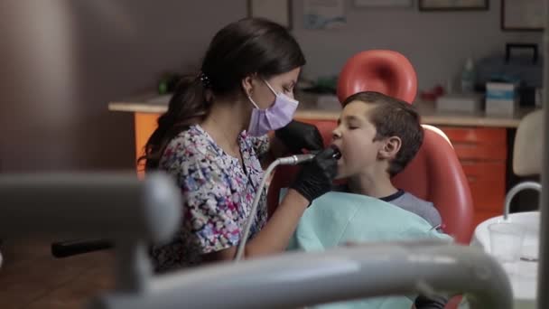 Un niño visita a un dentista, una doctora trata a un niño con dientes — Vídeo de stock