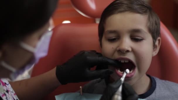 Un niño visita a un dentista, una doctora trata a un niño con dientes — Vídeos de Stock