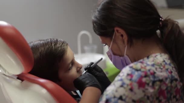 A boy visits a dentist, a woman doctor treats a childs teeth — Stock Video