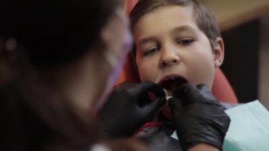 Küçük çocuk dişçi koltuğu açık ağzı ile oturmak