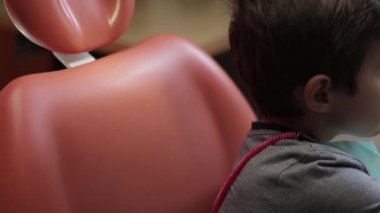 Küçük çocuk dişçi koltuğu açık ağzı ile oturmak.