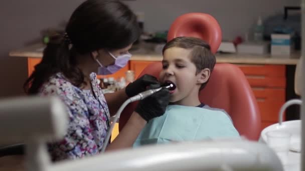 Niño en el dentista sentarse en la silla con la boca abierta — Vídeo de stock