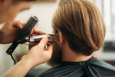 Bir saç kesimi saç kesme makineleri ile sahip sakallı adam. Closeup görünümü ile sığ derinlik-in tarla