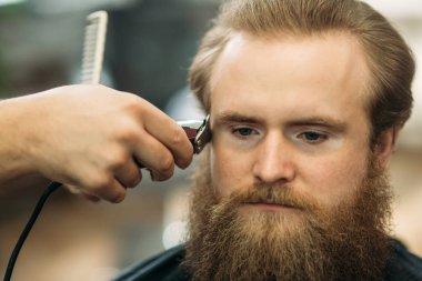 Bir saç kesimi saç kesme makineleri ile sahip sakallı adam. Closeup görünümü ile sığ derinlik-in tarla