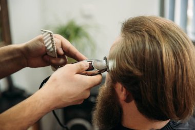 Bir saç kesimi saç kesme makineleri ile sahip sakallı adam. Closeup görünümü ile sığ derinlik-in tarla