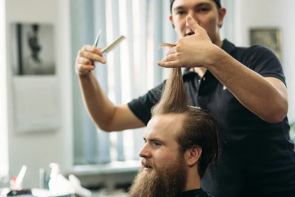 Barber using scissors and comb in barbershop