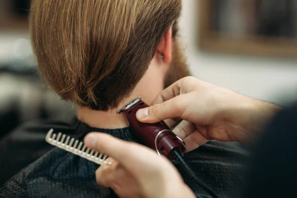 Hombre barbudo con un corte de pelo con un cortador de pelo. Vista de primer plano con poca profundidad de campo — Foto de Stock