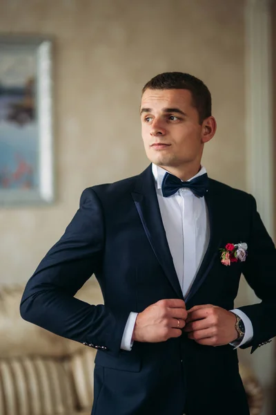 El novio está vestido de traje en casa. Lindo novio posando para un fotógrafo — Foto de Stock