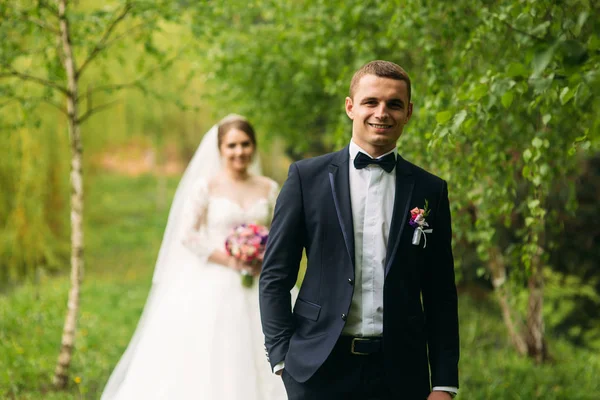 Nygifta vandrar i parken på bröllopsdagen. Bruden och brudgummen njuter på bröllopsdagen — Stockfoto