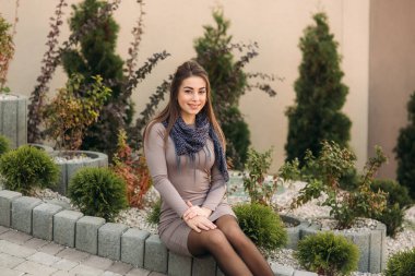 Bayan kaldırım kenarında oturur ve fotoğrafçı için poz veriyor. Sonbahar photosession