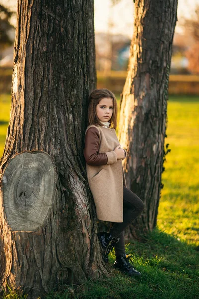 Dziewczynka w jesienny płaszcz pozowanie dla fotografa. Złota Jesień — Zdjęcie stockowe